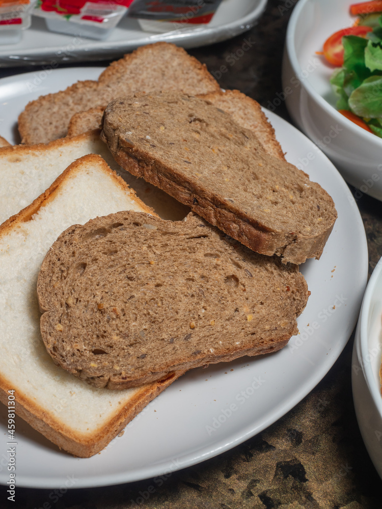Sice of white and whole grain breads in the white plate.