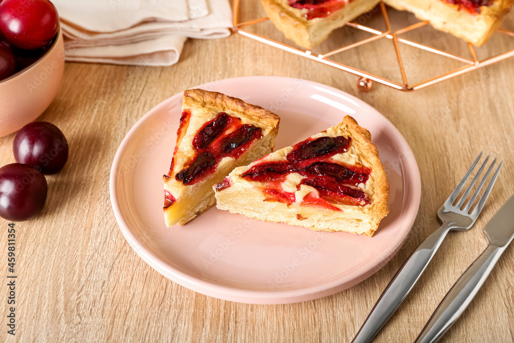 Plate with pieces of tasty plum pie on wooden background, closeup Plate with pieces of tasty plum pie on wooden background, closeup
