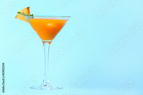 Glass of cold melon cocktail on blue background