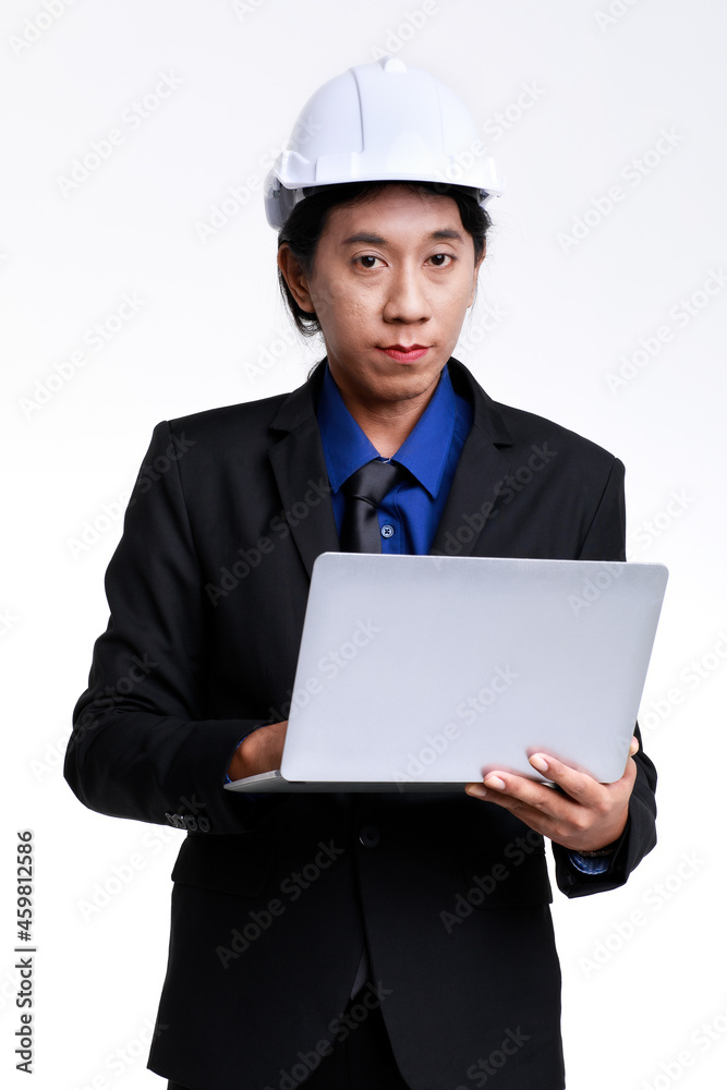 Isolated studio shot of Asian professional successful male foreman industrial engineer in black formal suit and safety helmet standing typing report on laptop notebook computer on white background Isolated studio shot of Asian professional successful male foreman industrial engineer in black formal suit and safety helmet standing typing report on laptop notebook computer on white background