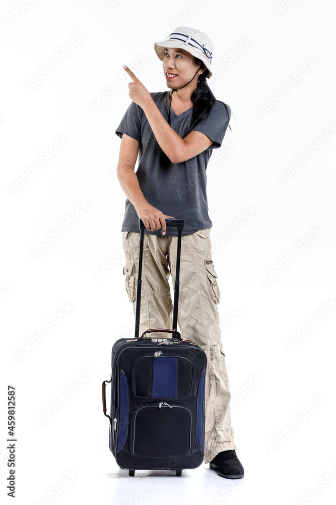 Isolated studio shot of Asian happy long hair ponytail male adventure traveler standing pointing on blank space for ads holding trolley traveling luggage for holiday vacation on white background