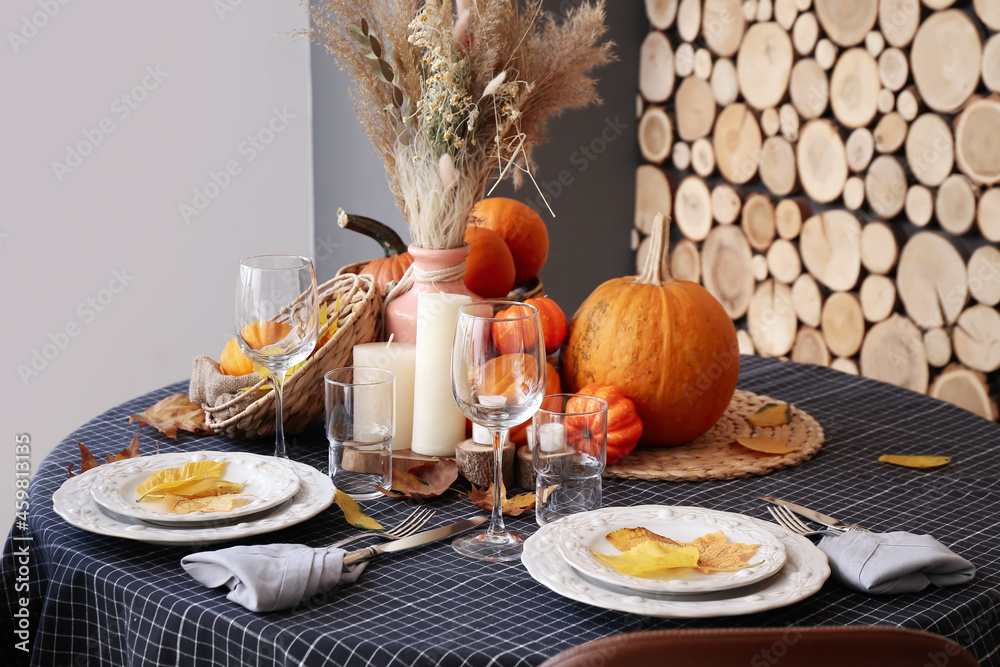 Autumn table setting with fresh pumpkins and leaves in room Autumn table setting with fresh pumpkins and leaves in room