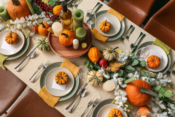 Autumn table setting with fresh pumpkins and flowers in room