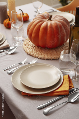 Autumn table setting with fresh pumpkin in room