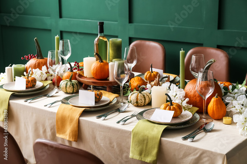 Autumn table setting with fresh pumpkins and flowers near green wall photo