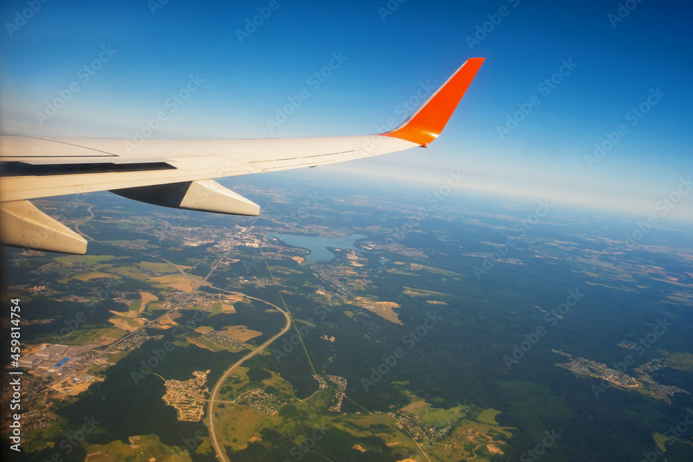 Fototapeta premium Classic image through aircraft window onto wing. Flight view over Russia