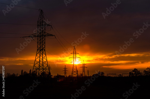 High voltage power line at sunset. Silhouettes of the metal pillars © ihorbondarenko