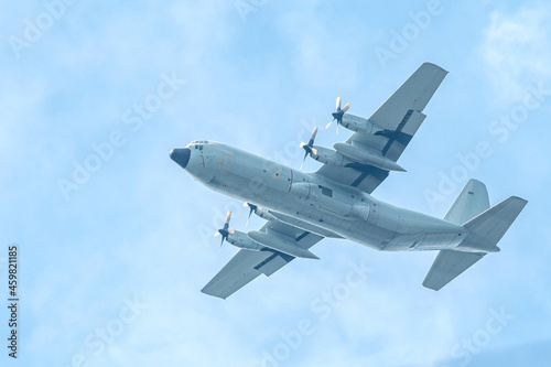 Military transport aircraft conducting training flight in the blue sky background.