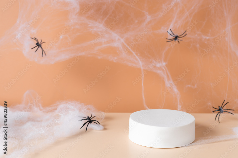 Obraz premium White podium with spider web and spiders on an orange background. product display. Simple modern autumn design
