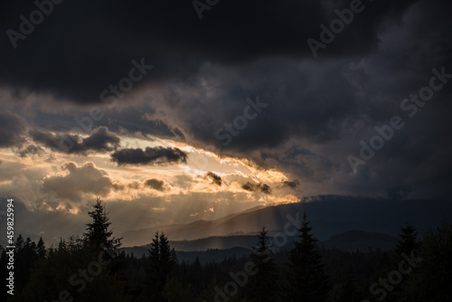 Sunbeams going through dark clouds over majestic mountains