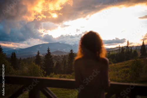 Back view of woman enjoying view of mountains during sunset