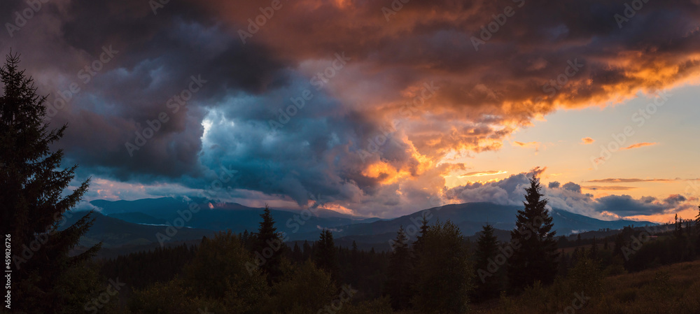 Fascinating summer sunset and heavy clouds over high mountains