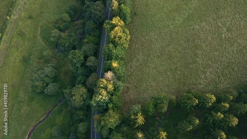 Cars moving on countryside road throughrural fields and tree forest, aerial view. Car trip at summer vacation photo