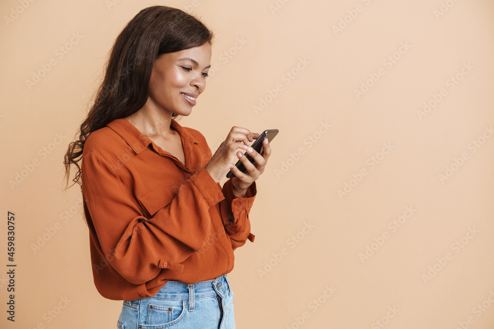 Young black woman wearing shirt smiling and using mobile phone Young black woman wearing shirt smiling and using mobile phone