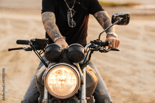 Senior man with tattoo posing on motorcycle outdoors