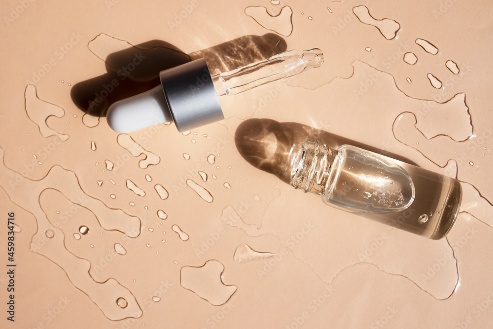 Glass bottle with cosmetic liquid on a beige background. Flat lay, place for text. Glass bottle with cosmetic liquid on a beige background. Flat lay, place for text.