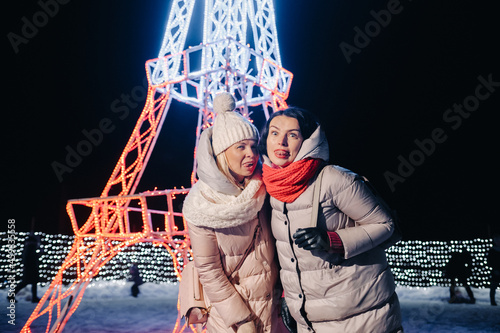 two girls in winter with New Year's eve lights burning on Christmas street photo