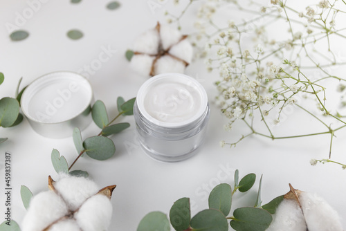 a jar of white cream on the background of plant branches