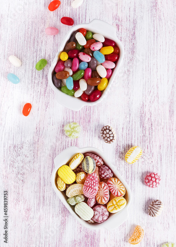 Two white ceramic bowls with colorful candies and jelly beans. Top view.