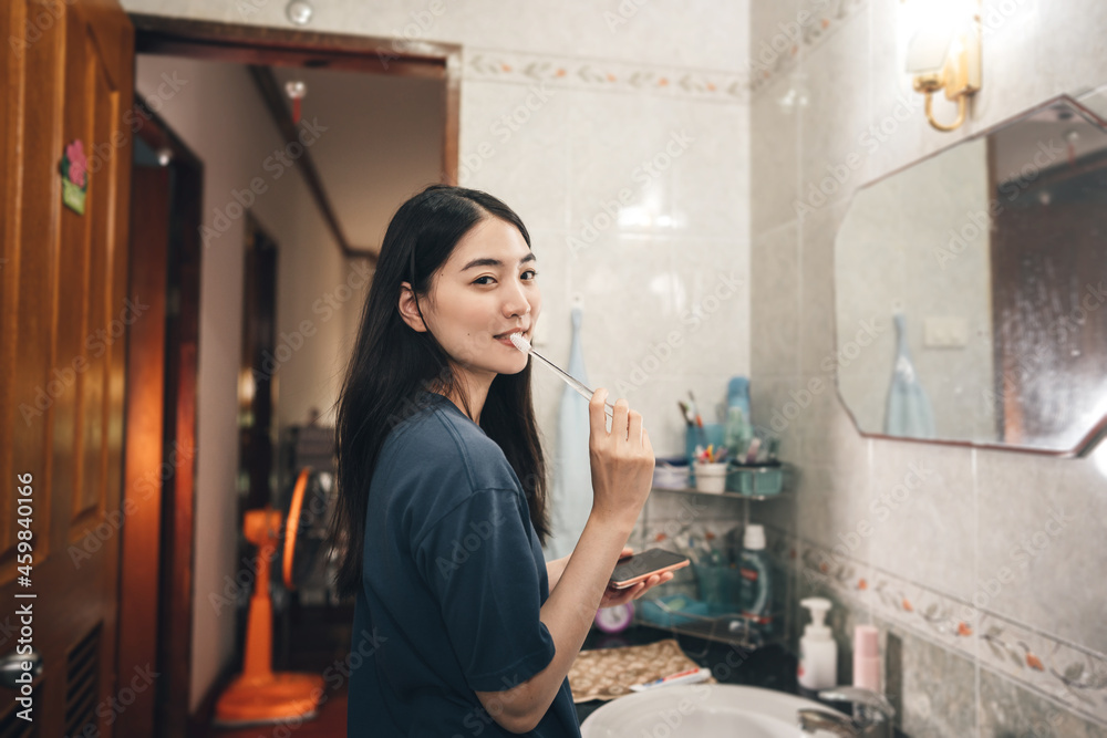 Portrait of young adult asian woman brushing teeth in font of bathroom mirror. Portrait of young adult asian woman brushing teeth in font of bathroom mirror.