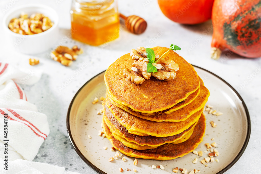 Pumpkin pancakes in a ceramic plate on a light gray culinary background close-up	