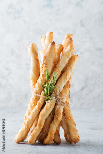 Italian grissini breadsticks with sesame and rosemary on a light background, selective focus photo