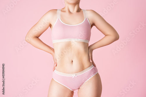 Flat stomach, slim woman in underwear on pink background