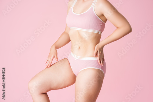 Flat stomach, slim woman in underwear on pink background