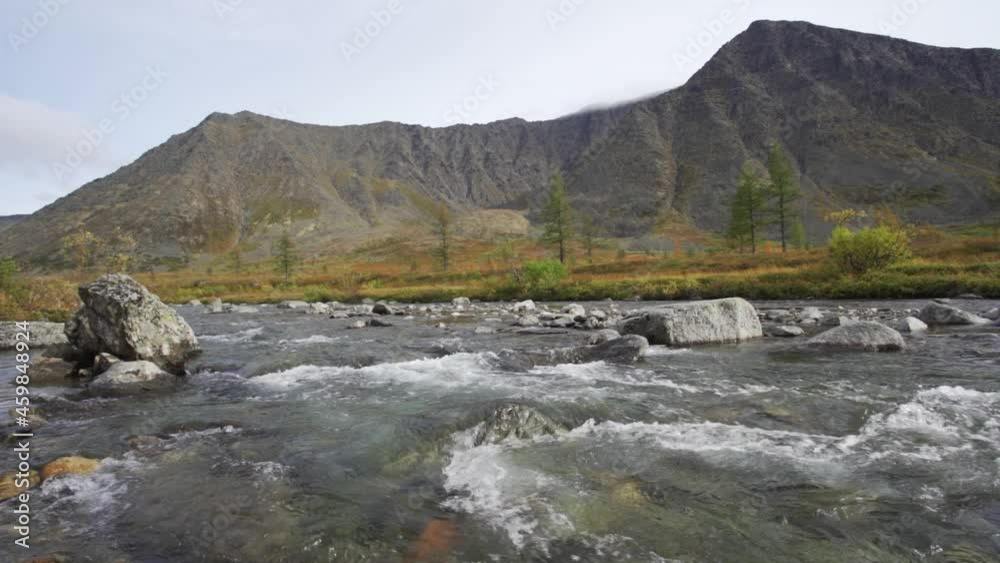 A fast, cold river flows through fields and mountains. Rough current and large stones. Camping romance. 4K UHD A fast, cold river flows through fields and mountains. Rough current and large stones. Camping romance. 4K UHD