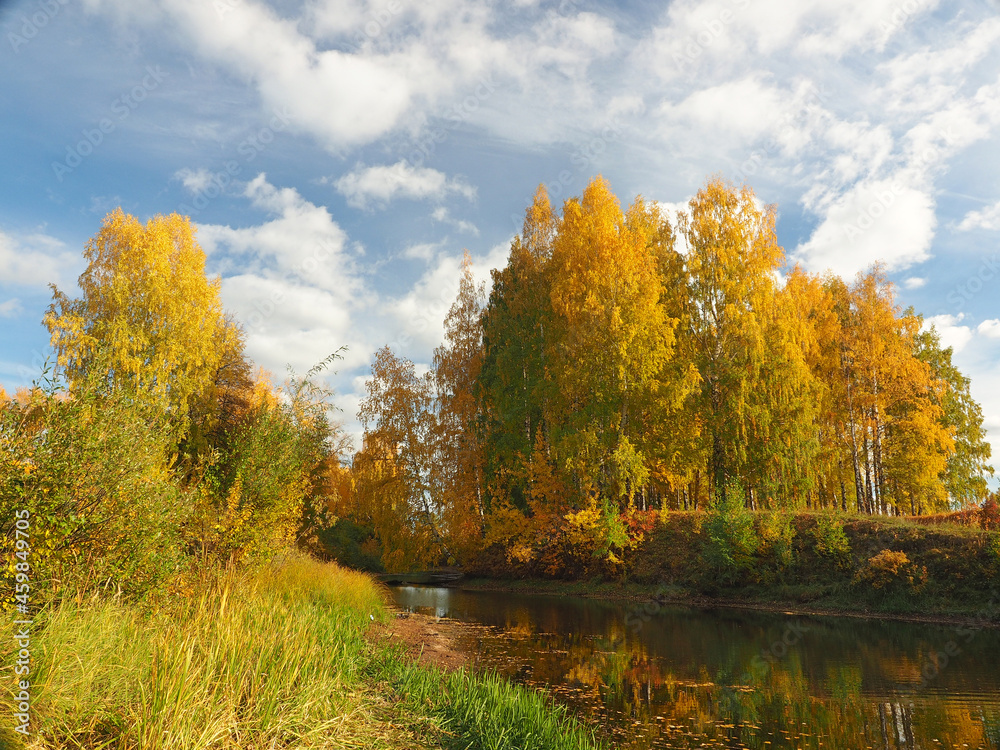 Autumn. Autumn trees in the park. River bay with floating leaves. Beautiful sky. Russia, Ural, Perm region