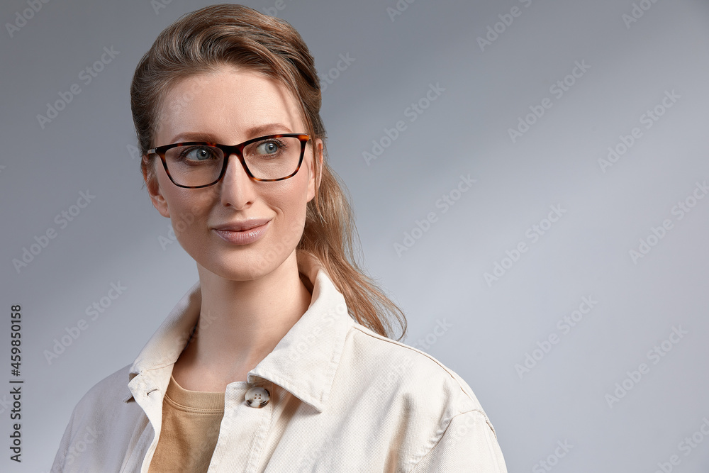 Confident young business woman 35-45 years old, blonde stilish formal clothes and glasses, gray background, close-up. Business and career success concept.