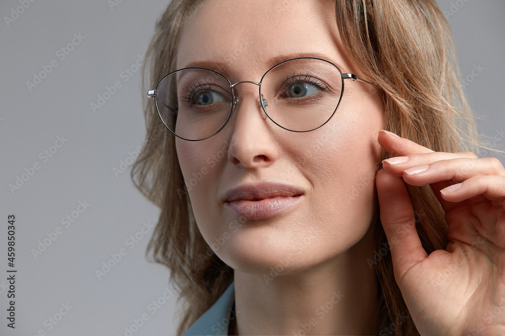 Confident young business woman 35-45 years old, blonde stilish formal clothes and glasses, gray background, close-up. Business and career success concept. Confident young business woman 35-45 years old, blonde stilish formal clothes and glasses, gray background, close-up. Business and career success concept.