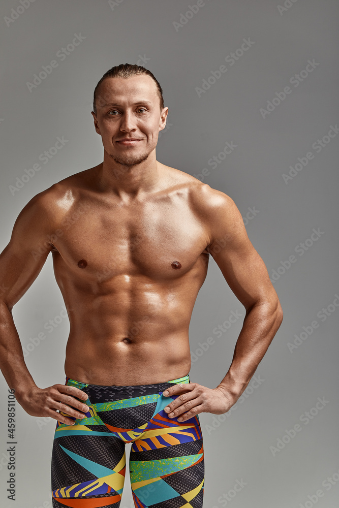 Fototapeta premium Portrait of a swimmer half-length portrait, young athlete swimmer in suit for swimming, copies of space, gray background. Motivation, advertising banner, place for text