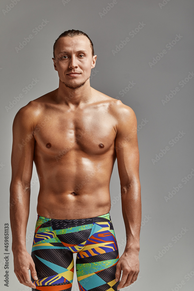 Fototapeta premium Portrait of a swimmer half-length portrait, young athlete swimmer in suit for swimming, copies of space, gray background. Motivation, advertising banner, place for text