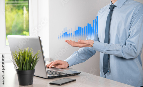 Business man holding tablet and showing holographic graphs and stock market statistics gain profits. Concept of growth planning and business strategy. Display of good economy form digital screen.