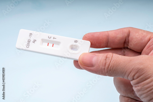 Hand holding Covid-19 Antigen Rapid test kits on white background. Test results result is positive.