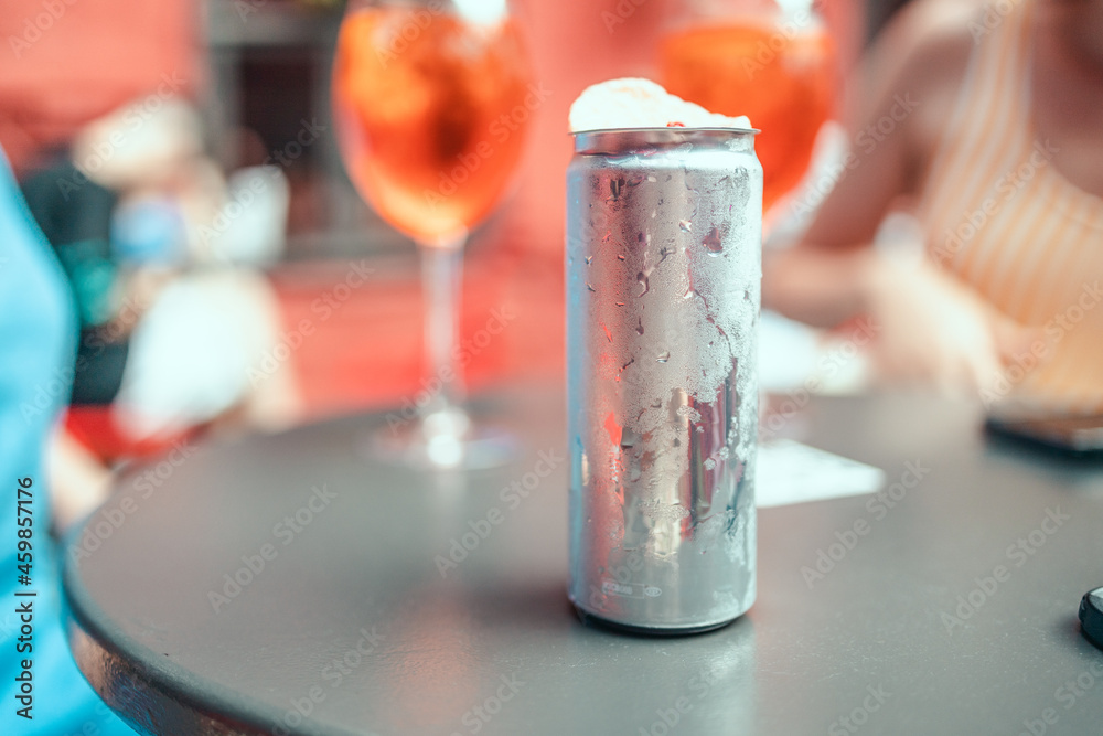 Summer cold aluminum can with alcoholic drink and decor on the table and light bokeh in an outdoor pub