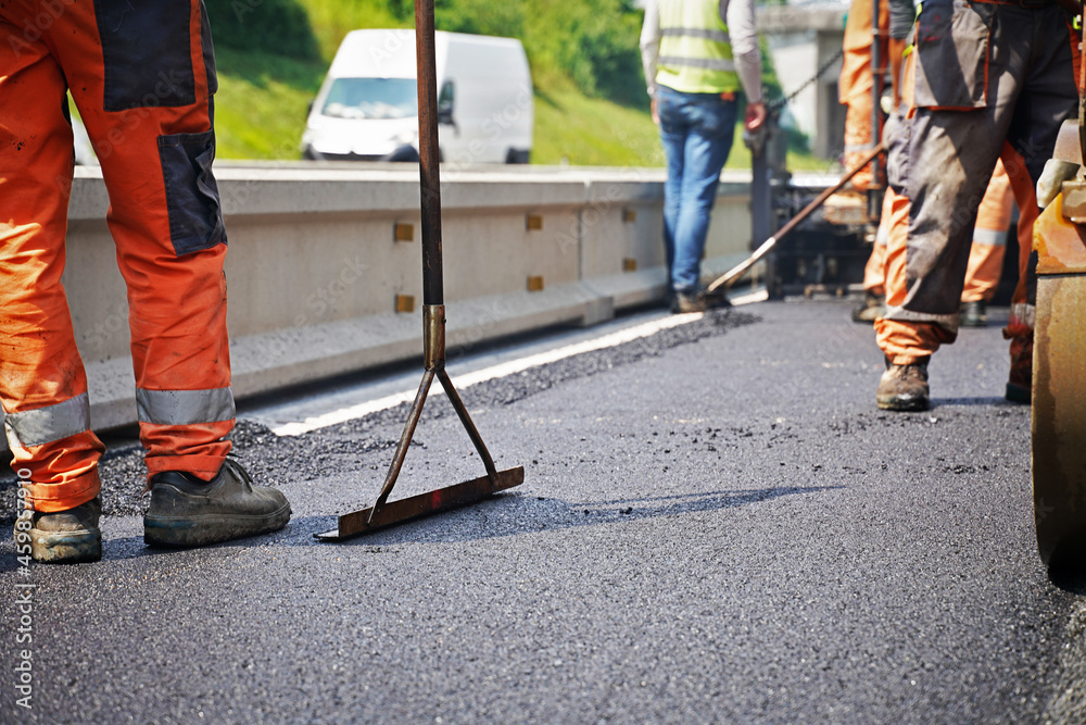 Workers in process of paving smoothing the road on a sunny day teamwork Workers in process of paving smoothing the road on a sunny day teamwork