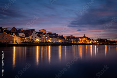 View from the Danube on the Regensburg Cathedral and Stone Bridge with lights in Regensburg in the evening  Germany