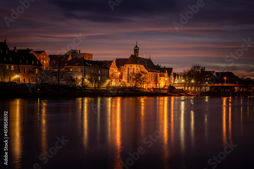 View from the Danube on the Regensburg Cathedral and Stone Bridge with lights in Regensburg in the evening, Germany