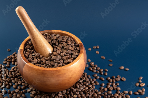 Coffee beans in a wooden mortar. Manual coffee grinder on a blue background. Copy space. Photo