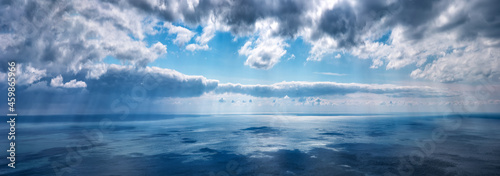 Clouds over the sea on a summer day with sunbeams  horizontally panoramic.