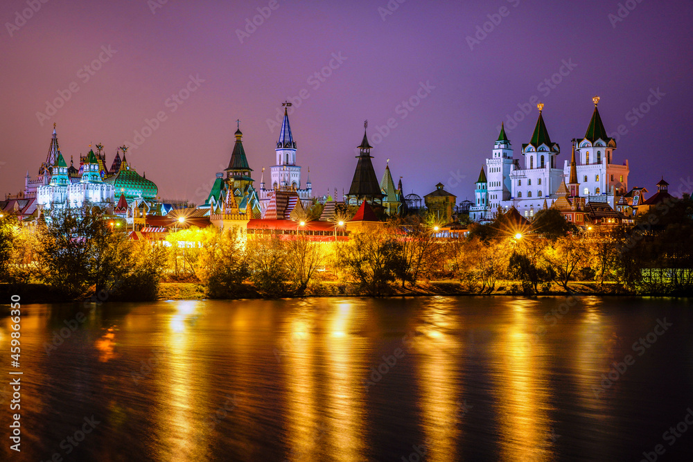 Panorama Izmailovo Kremlin buildings with turrets are illuminated by evening illumination against the background of a beautiful evening lilac embankment, on the banks of the reservoir the river. Panorama Izmailovo Kremlin buildings with turrets are illuminated by evening illumination against the background of a beautiful evening lilac embankment, on the banks of the reservoir the river.