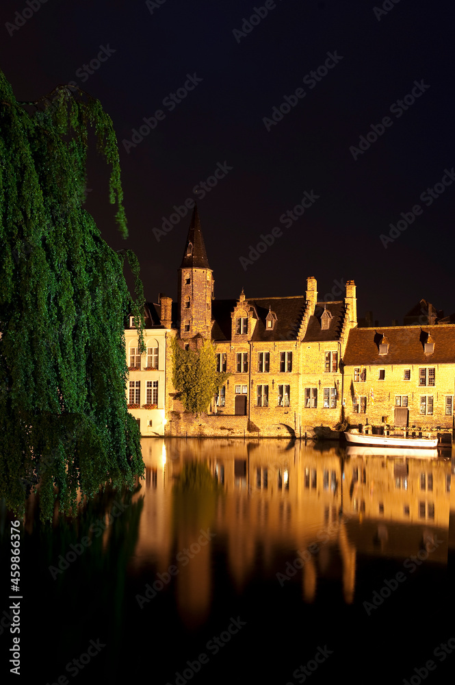 Romantic evening view of the canal, illuminated by old town lights and reflections in the water, Bruges, Belgium