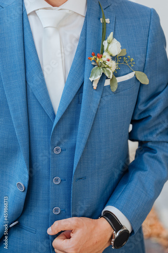 Groom in a blue jacket and beautiful flowers as a badge. Nice blue suit for wedding 