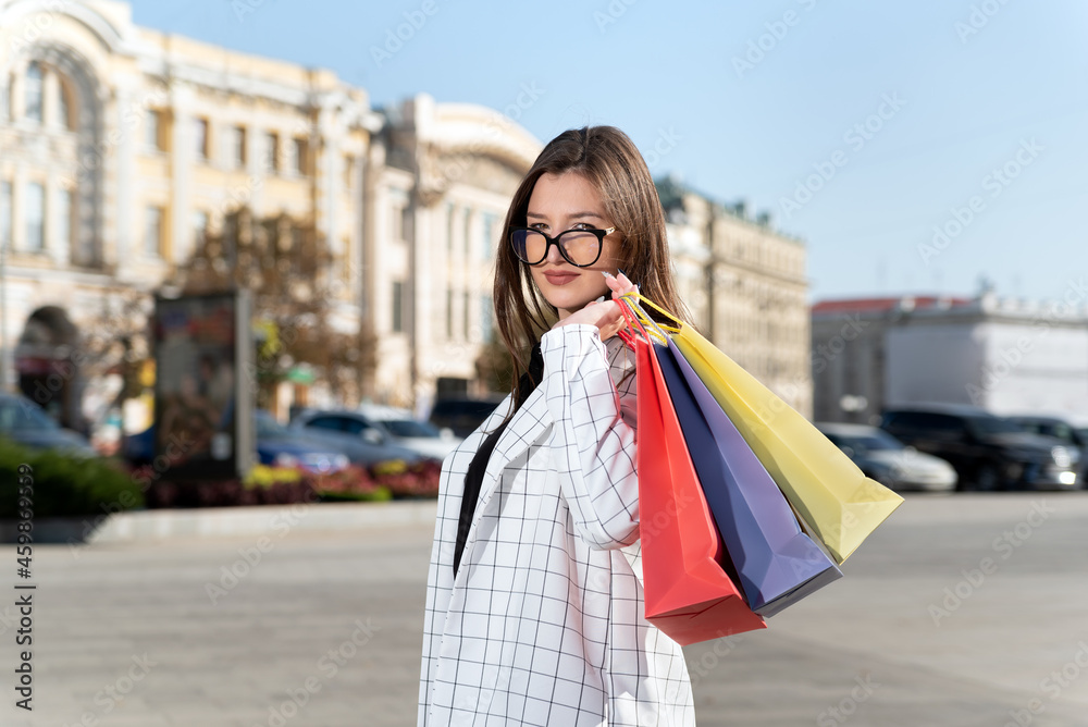 Portrait of stylish woman with shopping bags in hands on city background