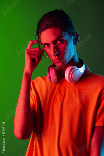 Portrait of young handsome man, student in casual clothes isolated on green vintage studio backgroud. Human emotions concept. © master1305