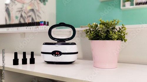 a sterilizer for manicure tools is on the table by the mirror. Professional equipment for sterilization of manicure tools. Beauty salon.Ultrasonic sterilizer.

