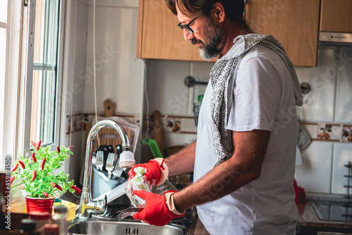 Mature man cleaning glass in kitchen photo