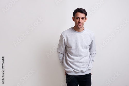 Attractive young stylish man in grey jumper and jeans, isolated white background.